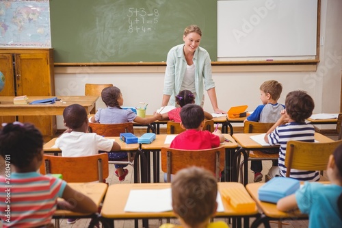 Pretty teacher talking to the young pupils in classroom