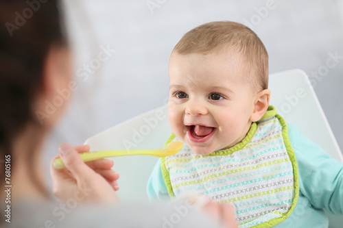 Mother giving fruit sauce to baby boy