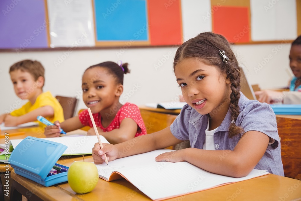 Cute pupils writing at desk in classroom Cute pupils writing at desk in classroom