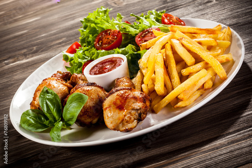 Grilled chicken legs with chips and vegetables