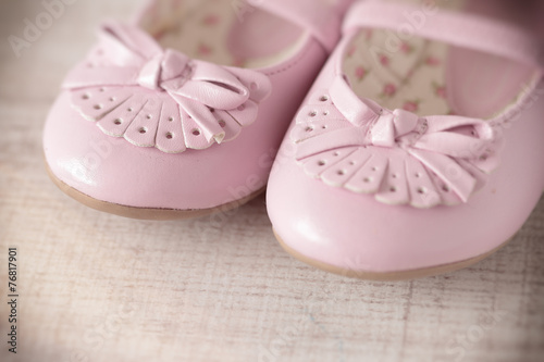 Detail of a pink girl shoes over wooden deck floor