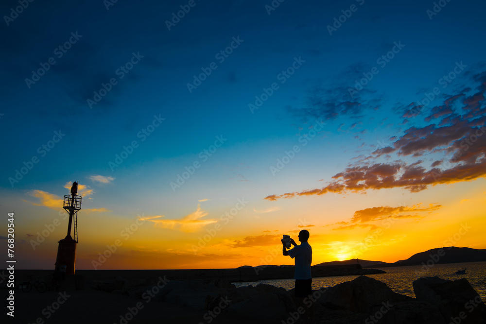 tourist and lighthouse at sunset