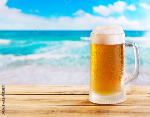 mug of beer on wooden table over sea