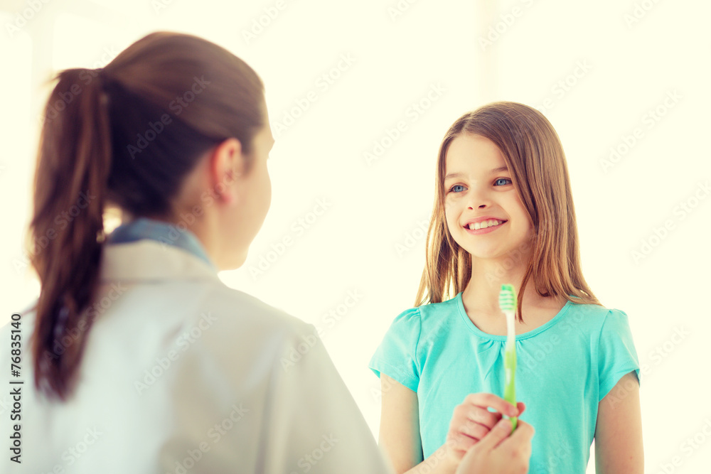 female doctor giving toothbrush to smiling girl female doctor giving toothbrush to smiling girl