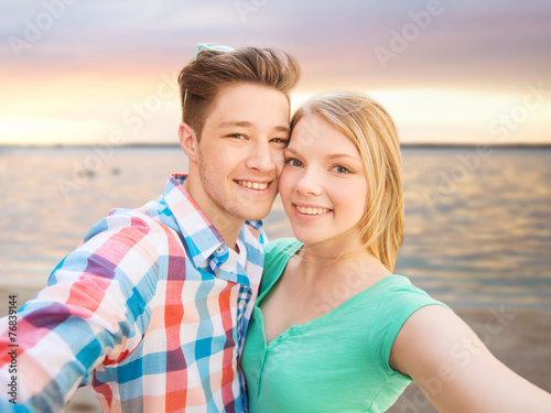 smiling couple with smartphone on summer beach