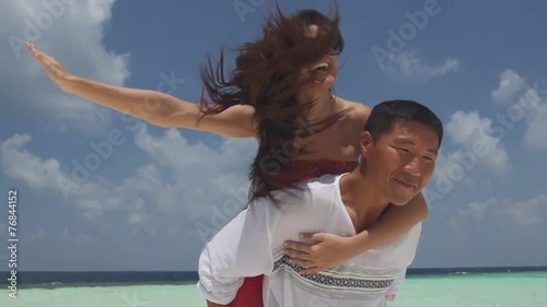 Asian Man Gives His Girlfriend Piggyback Ride On Romantic Island Of Maldives photo