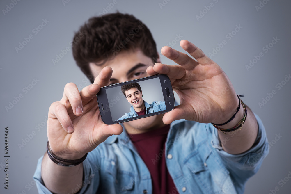 Teenager taking selfies with his smartphone