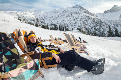 Man sits on sun-lounger in alpian ski resort