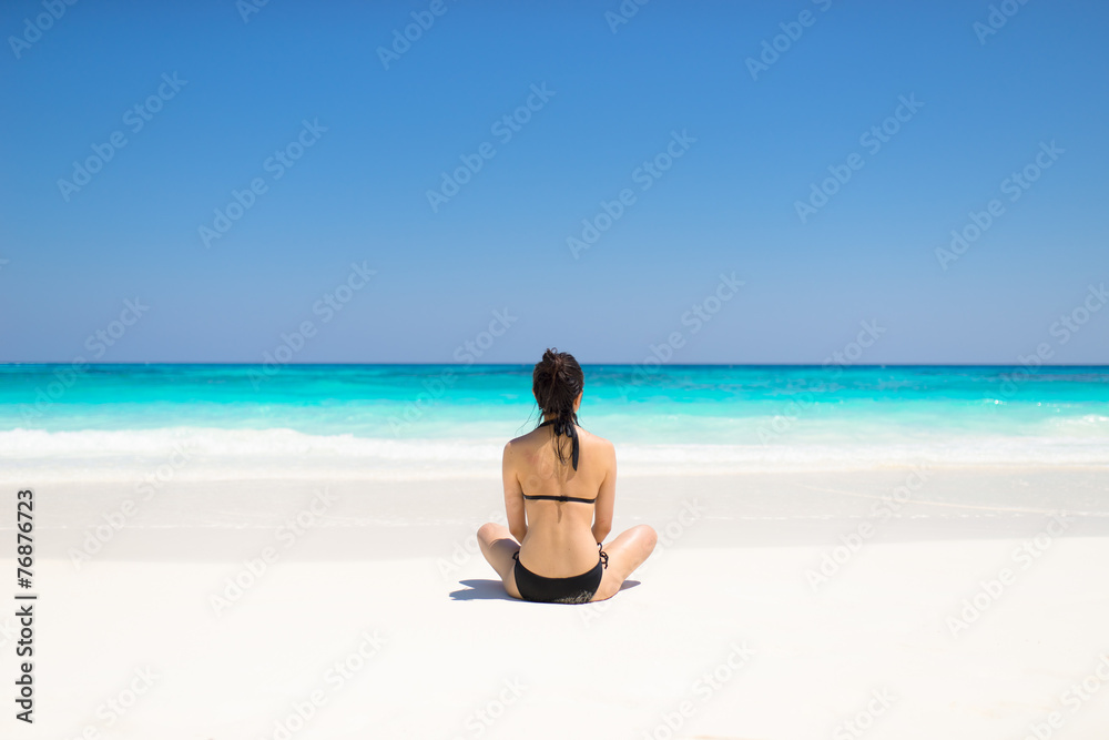 Bikini girl sitting on idyllic tropical beach paradise