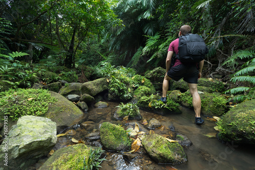 Man trekking through dense lush green tropical Jungle