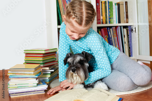 girl and her dog in glasses reading a book, sitting on floor in