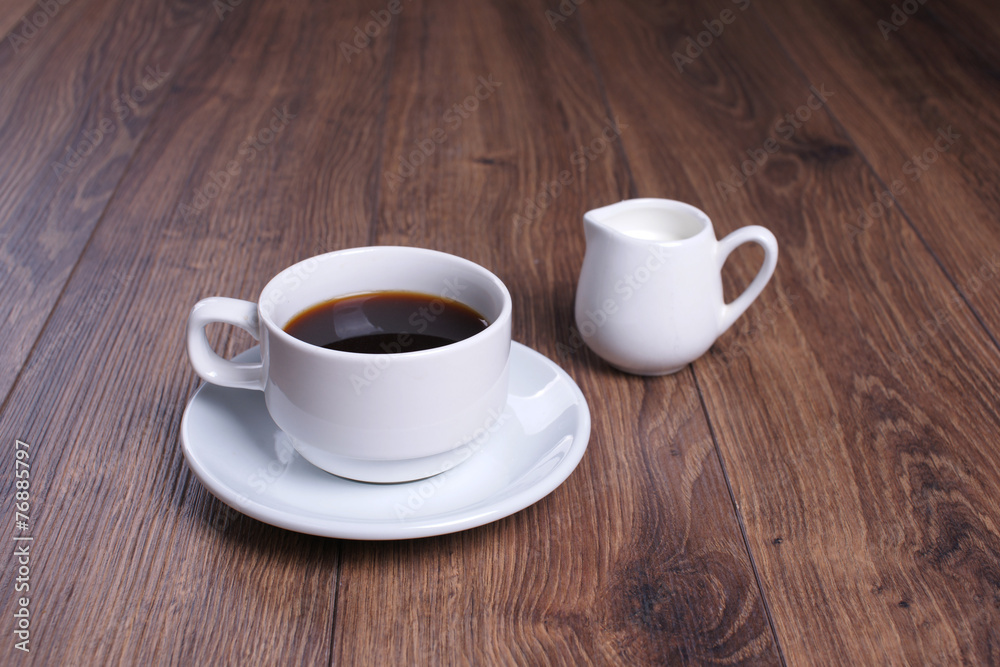 Кружка  с чёрным кофе и молочник на деревянном столе