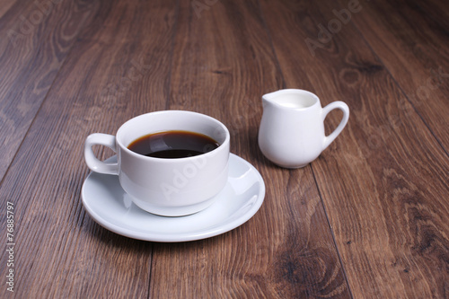 Кружка с чёрным кофе и молочник на деревянном столе