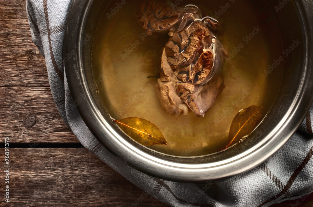 Meat broth from beef in a metal pan on the wooden table Meat broth from beef in a metal pan on the wooden table