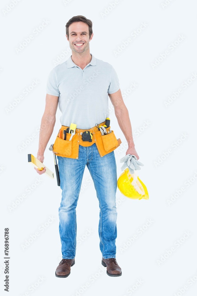 Happy repairman holding spirit level and hardhat Happy repairman holding spirit level and hardhat
