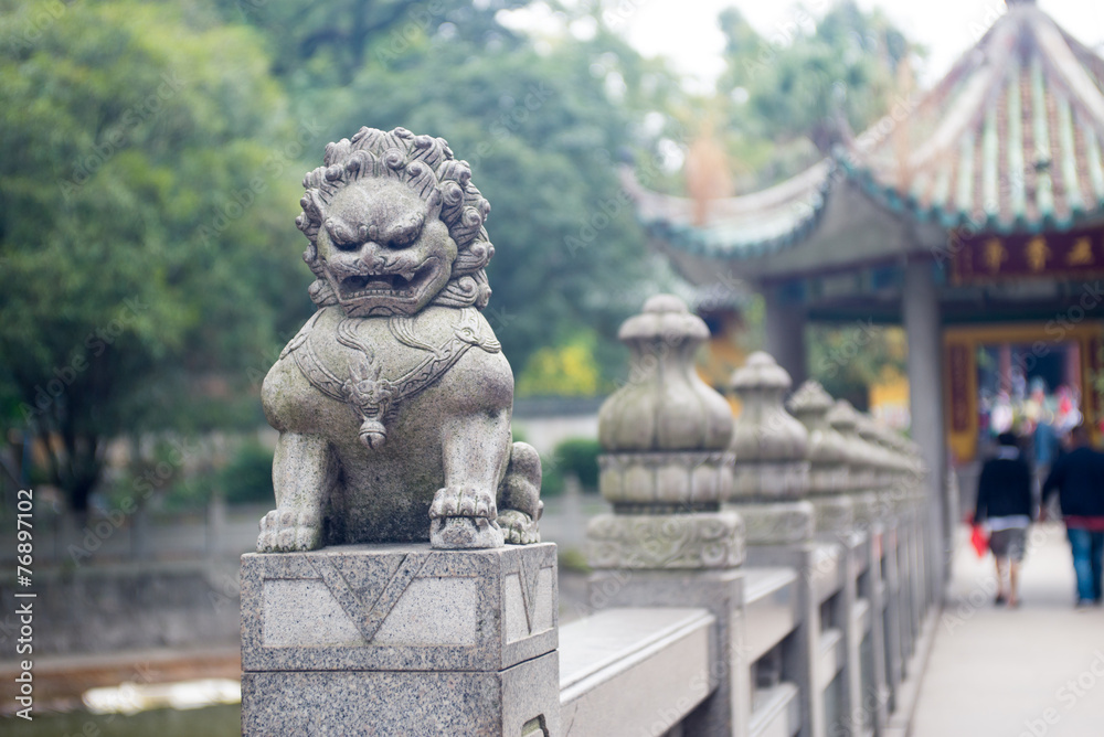 Obraz premium stone lion sculpture on the fence in the park