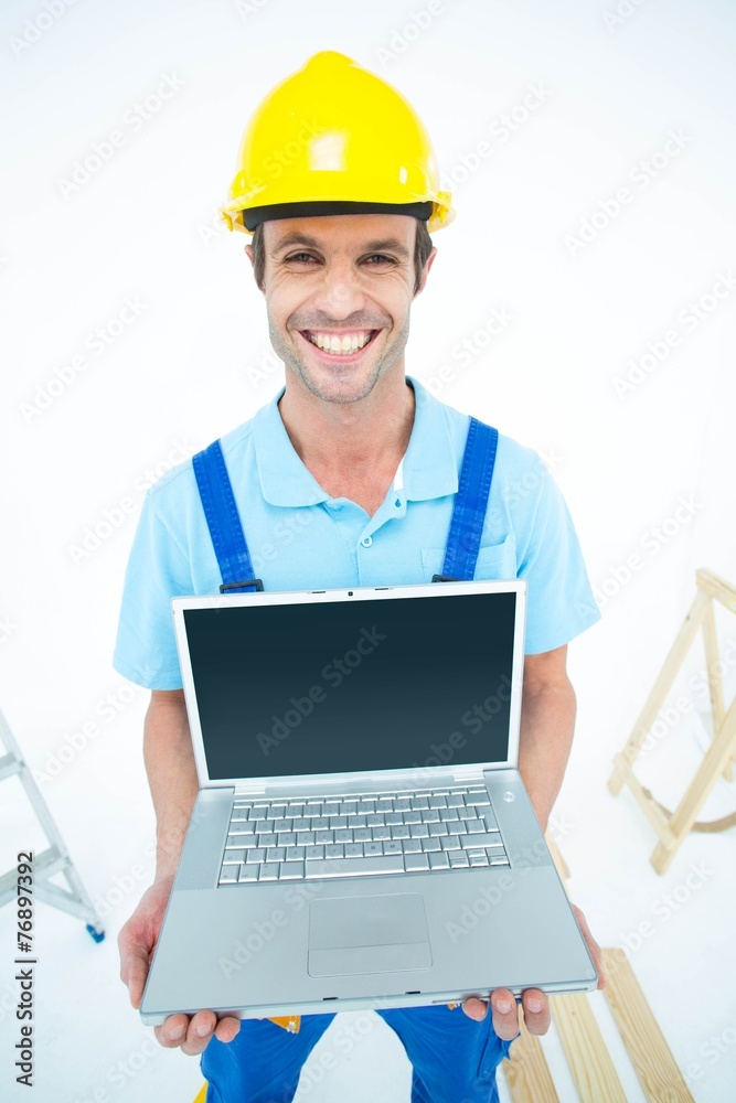 Happy repairman wearing hard hat while holding laptop Happy repairman wearing hard hat while holding laptop