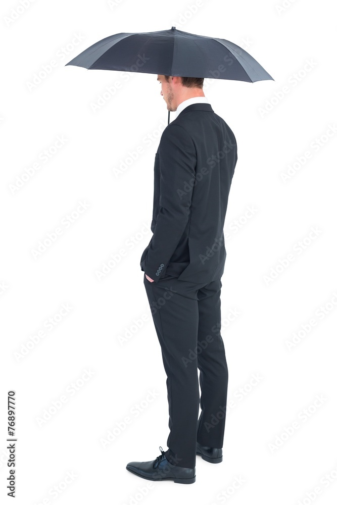 Businessman sheltering under black umbrella Businessman sheltering under black umbrella