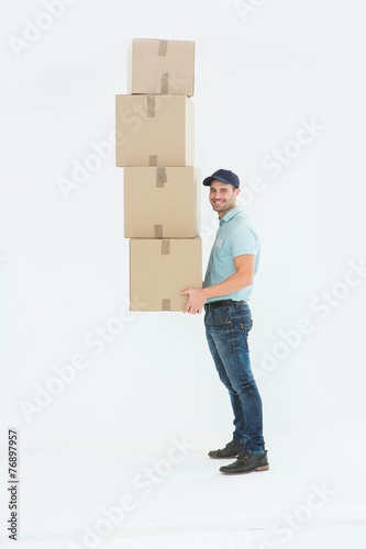 Confident delivery man carrying stack of boxes