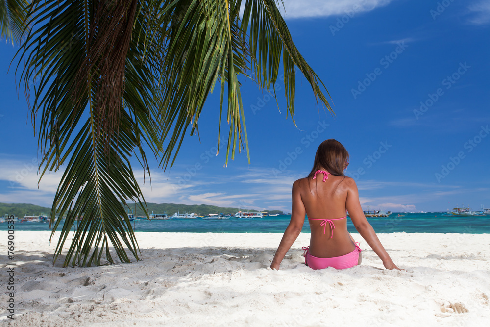 young girl resting on the beach under a palm tree young girl resting on the beach under a palm tree