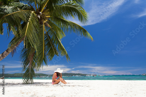 young girl resting on the beach under a palm tree © Pavel Morozov