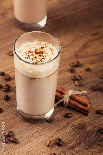 Full glass of milk cocktail and coffee beans on the wooden backg