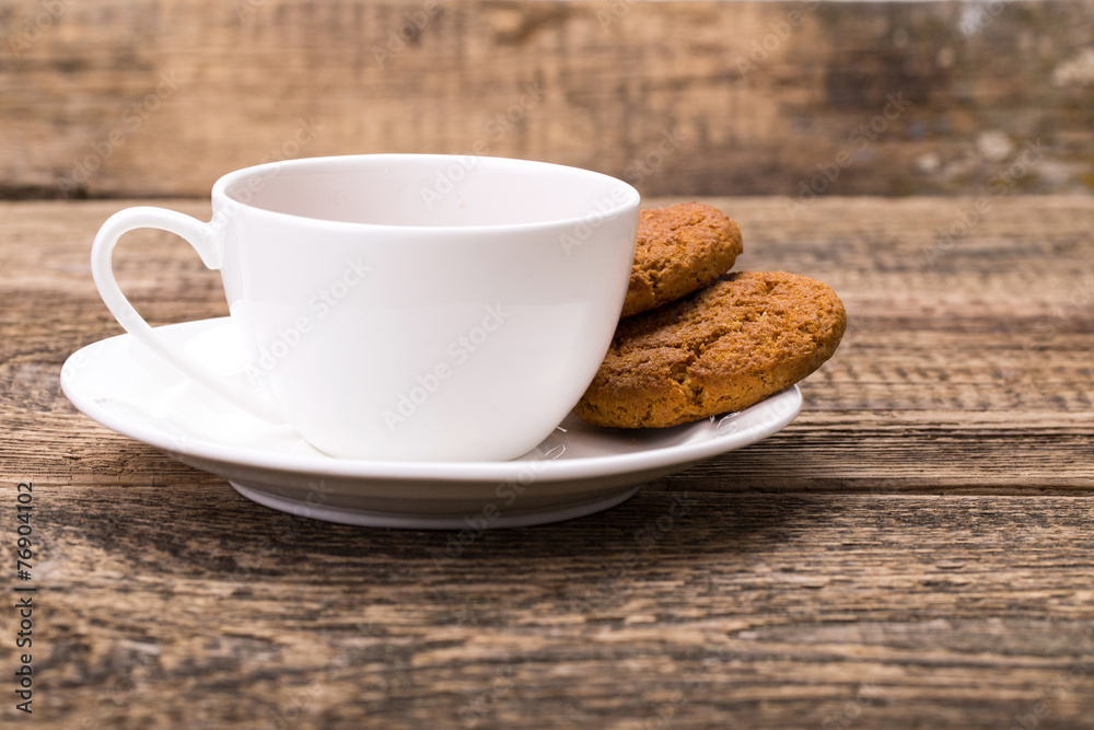 Ivory tea cup with sweet cookie on wooden palette Ivory tea cup with sweet cookie on wooden palette