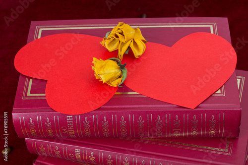 Two red hearts lying on the books with dried roses photo