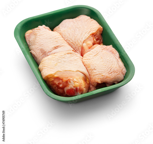 Photo Raw chicken thighs in a green tray over white background