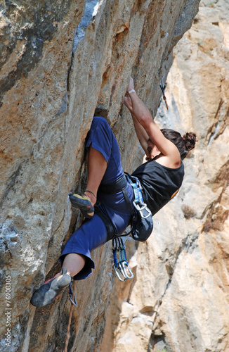 Girl climbing on the rock on background