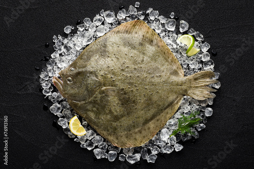 Fresh turbot fish on ice on a black stone table top view photo