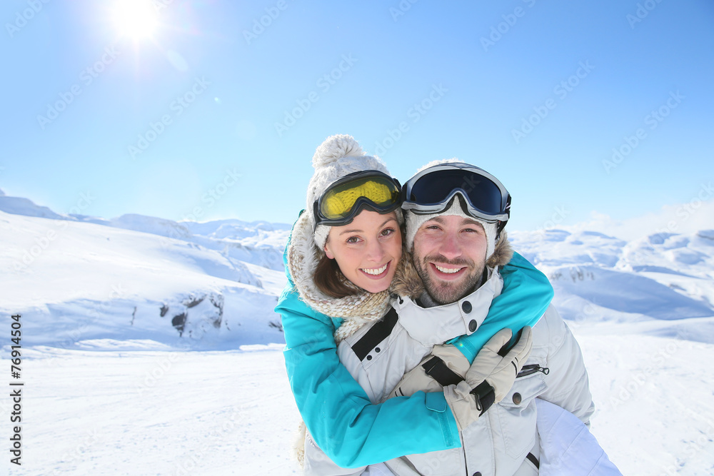 Man holding girlfriend on his back at the top of mountain
