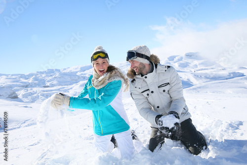 Couple in snowy mountain doing snowballs fight