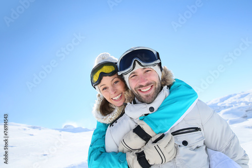 Man holding girlfriend on his back at the top of mountain