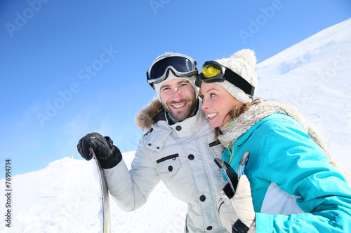 Cheerful couple of skiers ready to go down ski slope