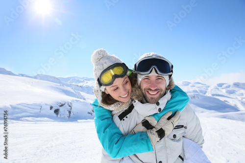 Man holding girlfriend on his back at the top of mountain