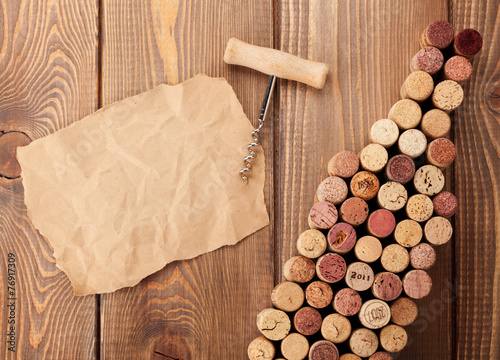 Wine bottle shaped corks, corkscrew and piece of paper