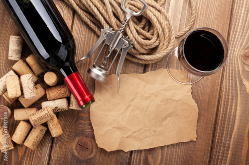 Red wine, corks, corkscrew and piece of paper