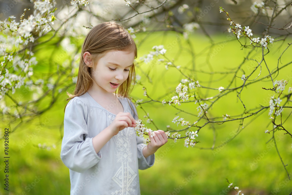 Adorable little girl in blooming cherry garden Adorable little girl in blooming cherry garden