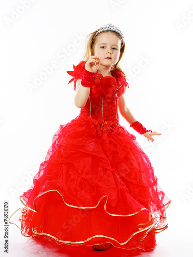 Cute little princess dressed in red with crown on her head posi