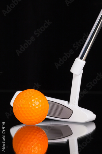Golf putter and gold equipments on the black glass desk