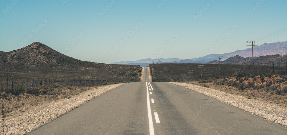 Endless road with blue sky in Swartberg semi desert landscape. W