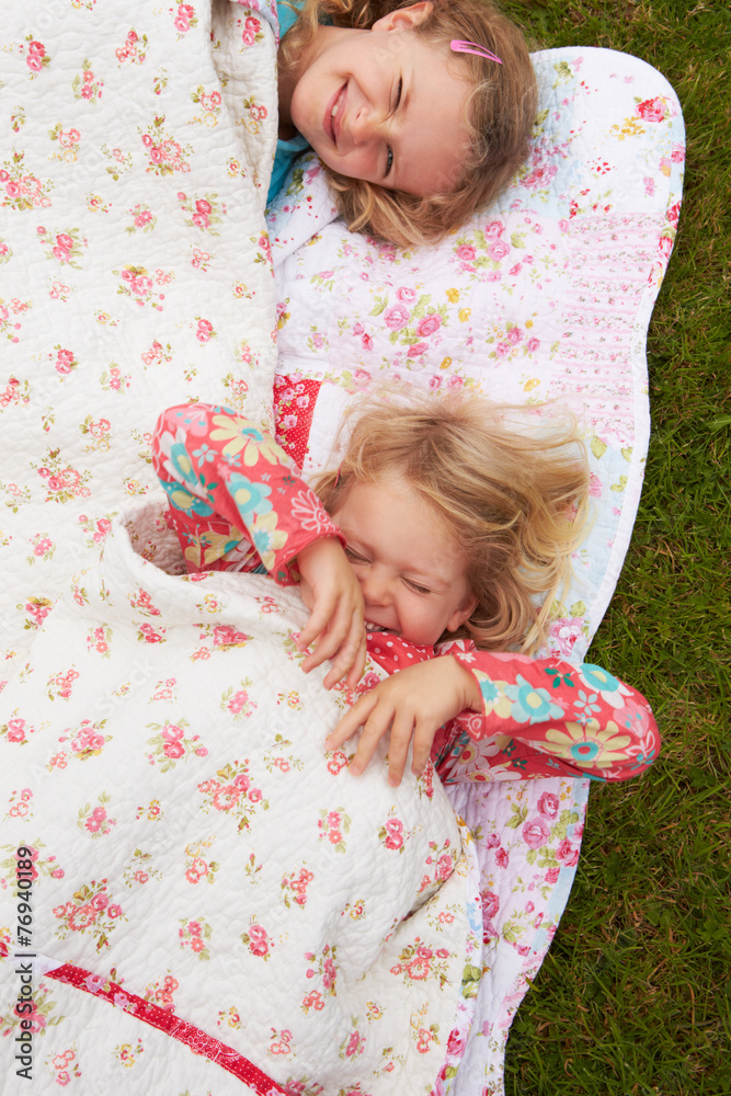 Two Girls Lying Under Blanket On Camping Holiday Two Girls Lying Under Blanket On Camping Holiday