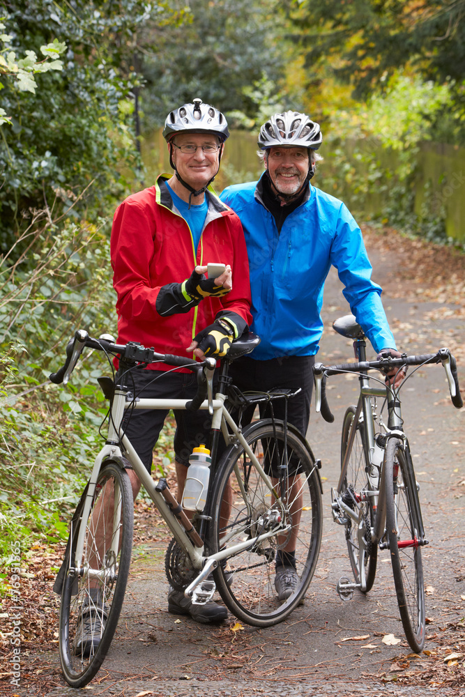 Two Mature Male Cyclists On Ride Looking At Mobile Phone App Two Mature Male Cyclists On Ride Looking At Mobile Phone App