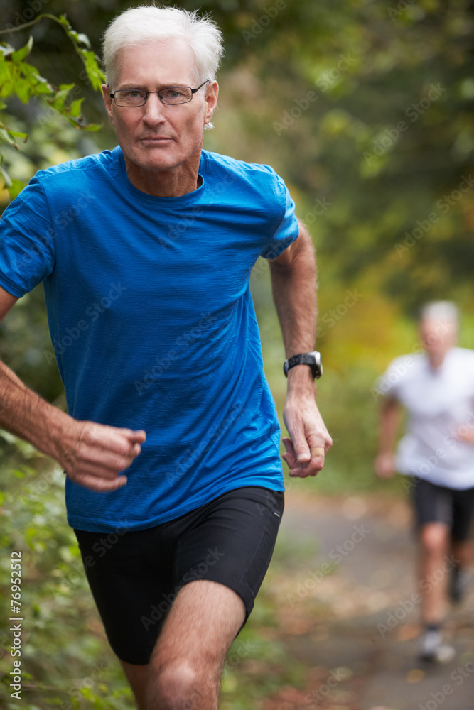 Two Mature Male Joggers Running Along Path Two Mature Male Joggers Running Along Path