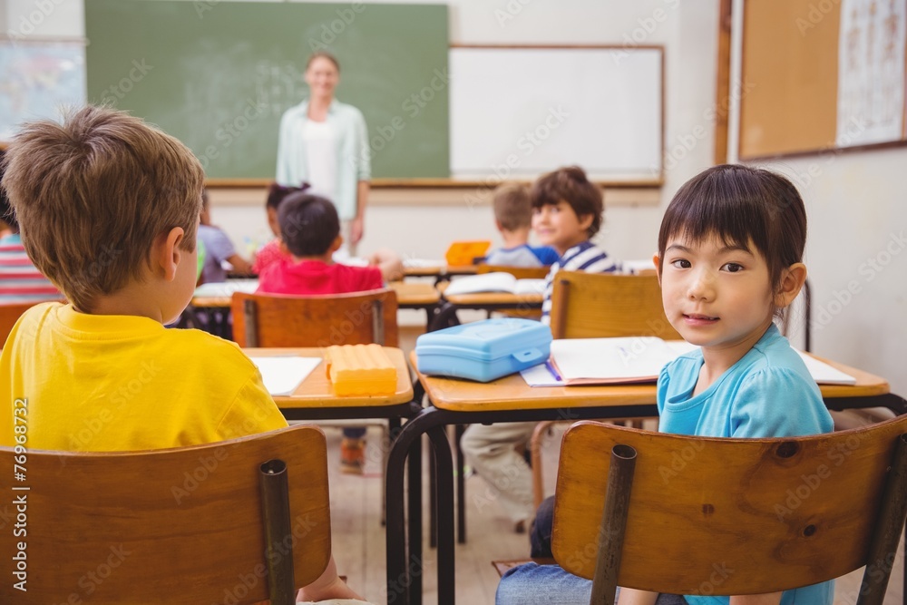 Cute pupil smiling at camera in classroom Cute pupil smiling at camera in classroom