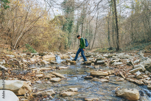 Obraz na plátně Hiker man crossing a river