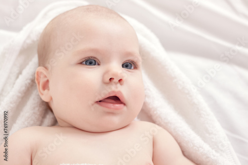 Beautiful baby relaxing in bed after bath