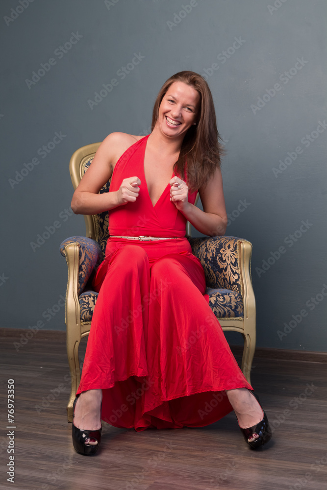 girl in red dress sitting on chair and shows fig Stock Photo | Adobe Stock