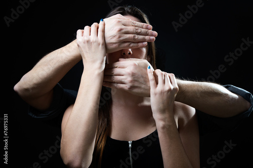 Young woman with eyes and mouth covered by a male hands. Handlin photo